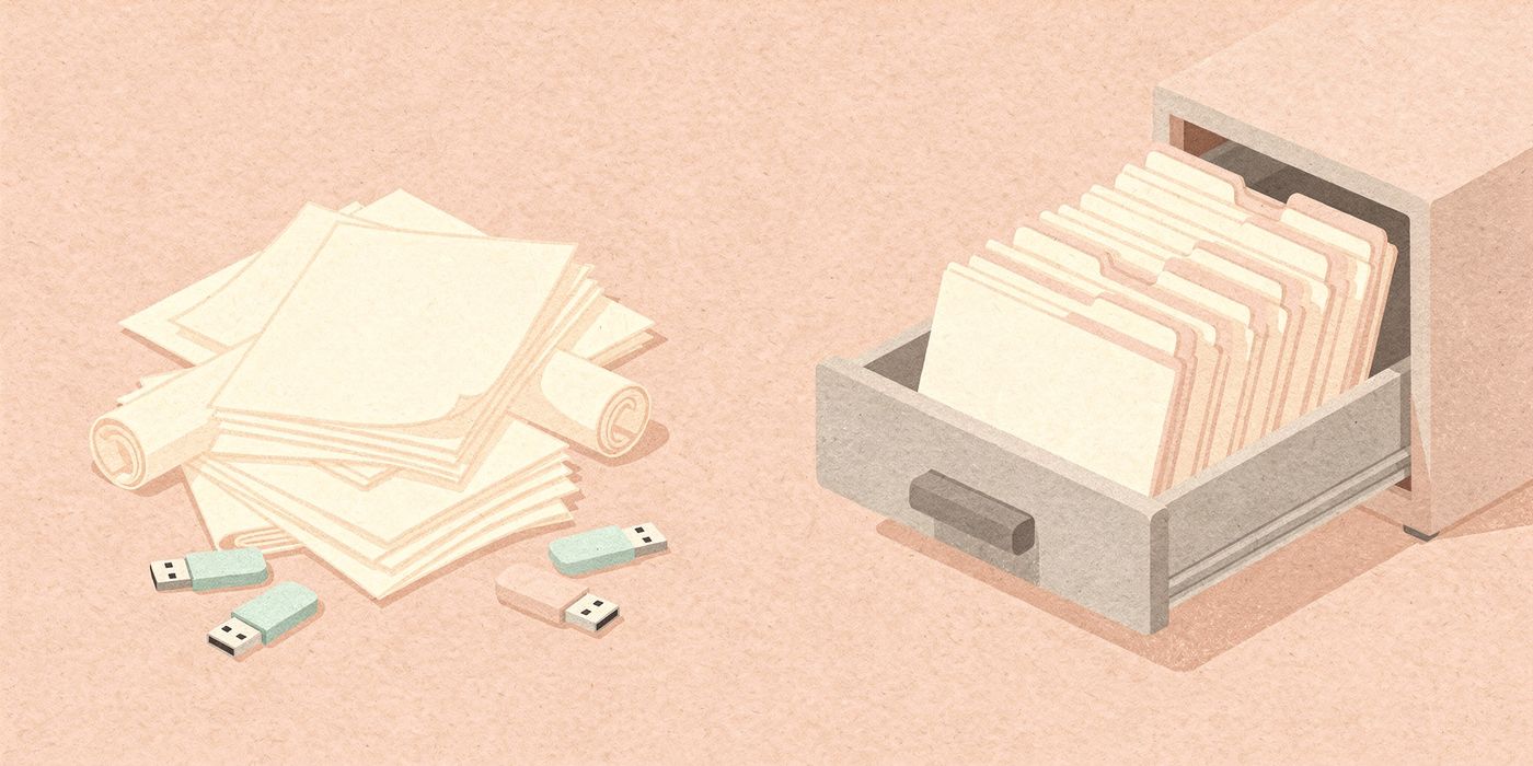A messy pile of drawings and USB sticks beside an open drawer of neat folders